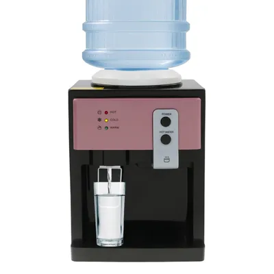 A desktop water cooler with a water bottle on top and a glass of water underneath.