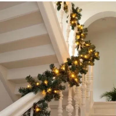 A Christmas garland with lights is draped along a staircase railing.