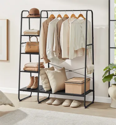 A clothing rack with clothes, bags, shoes, and pillows.