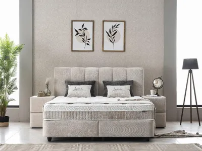 A bedroom scene featuring a boxspring bed, nightstands, artwork, and a floor lamp.