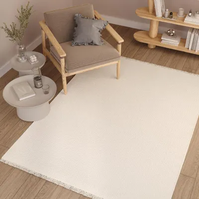 A modern living room scene with a chair, side tables, and a large rug.