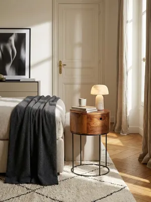 Runder Nachttisch aus Sheesham Massivholz neben einem Leinenbett in einem hellen, minimalistisch eingerichteten Schlafzimmer mit Holzboden._#sku_SAFWL6.849#
