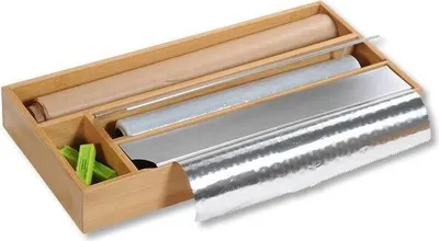 A wooden organizer for kitchen foil, plastic wrap, and parchment paper, with green clips in a separate compartment.