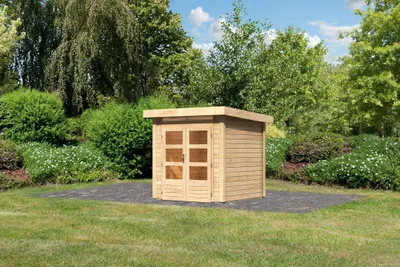 A wooden garden shed is situated on a paved area in a lush garden setting.