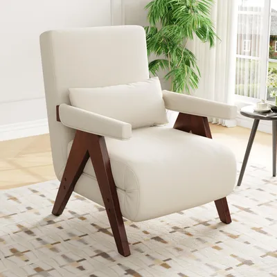 A cream-colored armchair with wooden legs and armrests, placed on a patterned rug in a well-lit room with a large window and a plant.