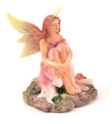 Hier ist eine süße kleine Feenfigur die auf Felsen sitzt. Sie hat wunderschöne, zart gefärbte Flügel