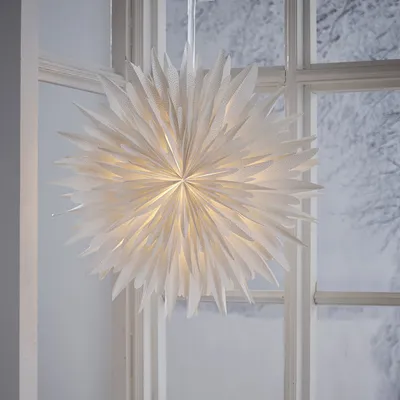 A large white paper star decoration hangs in a window with a snowy winter scene visible outside.