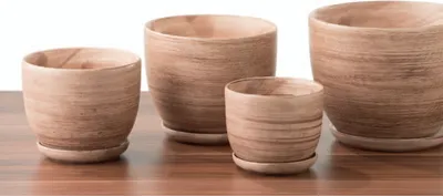 Four ceramic pots of varying sizes are arranged on a wooden surface against a white background.