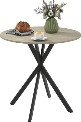 A round dining table with a bread roll, a cup of coffee, and a vase of flowers.