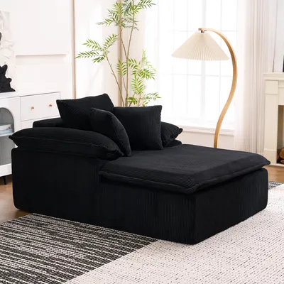 A black sofa with pillows in a living room setting, with a floor lamp and a plant.