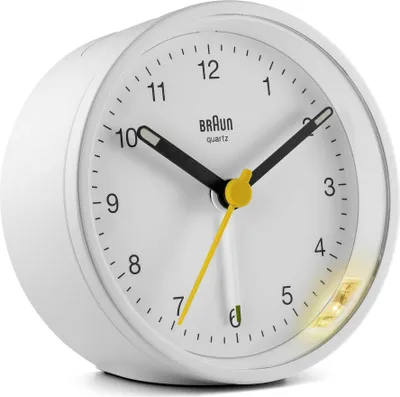 A white Braun alarm clock with black hands and yellow accents.