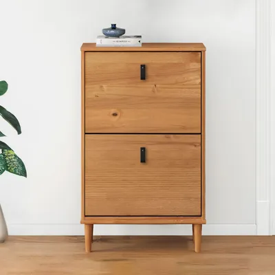 A wooden shoe cabinet with two flip-down doors and black handles, placed against a white wall.