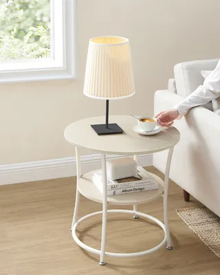 A person's hand reaches for a cup of coffee on a round side table next to a sofa.