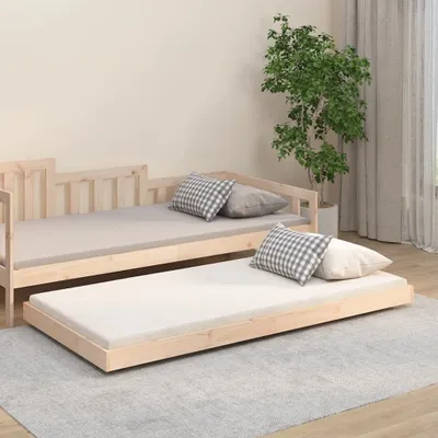 A wooden daybed with a pull-out trundle bed, both with mattresses and pillows, in a room with a plant and curtains.