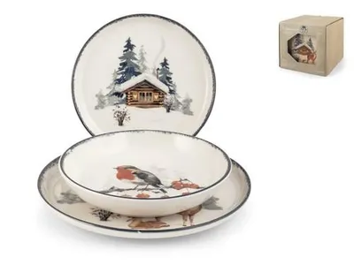 A set of dinnerware with a winter cabin and animal theme, including a plate, bowl, and another plate, along with a small box in the background.