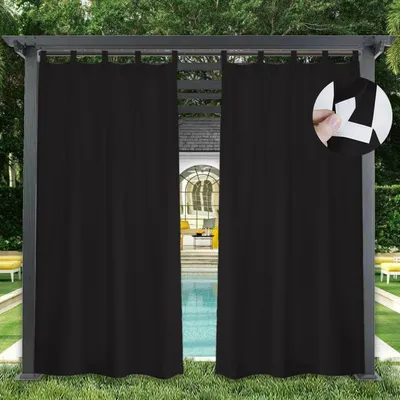 Black outdoor curtains hanging from a pergola, with a swimming pool and lounge chairs visible in the background.