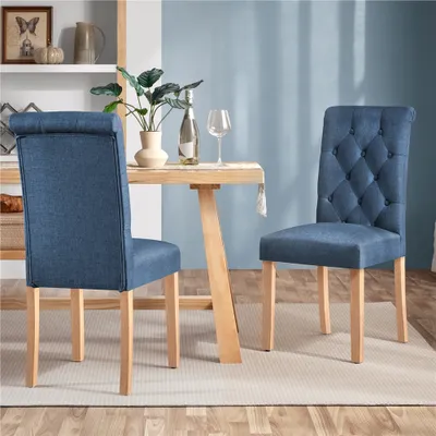 Two blue dining chairs are placed around a wooden dining table in a room with a blue wall.