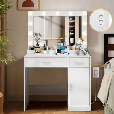 A white vanity table with a lighted mirror, drawers, and a cabinet, placed next to a bed.