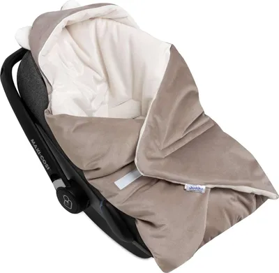 A baby car seat with a blanket draped over it.