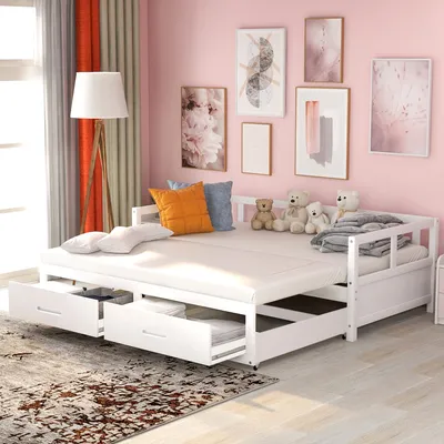 A white daybed with drawers pulled out, set against a pink wall with framed artwork and a floor lamp.