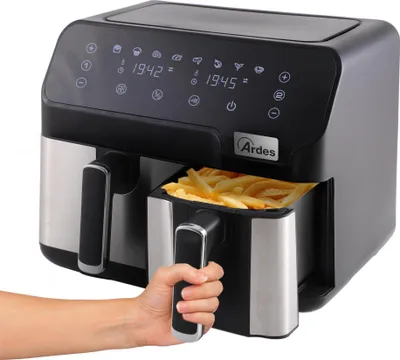 A hand is shown pulling out a basket of french fries from a dual-basket air fryer.