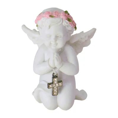 A white angel figurine kneeling with its hands clasped and a cross pendant hanging from its hands. The angel has a wreath of pink roses and green leaves on its head.
