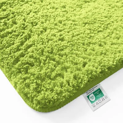 Close-up of a fluffy green bath mat with a label attached.