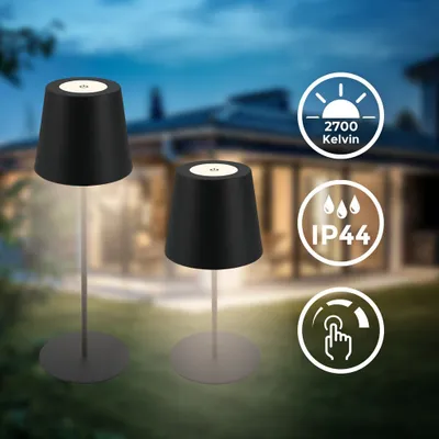 Two black table lamps are shown in a garden setting at dusk, with a house in the background. Icons indicating features are displayed on the right.