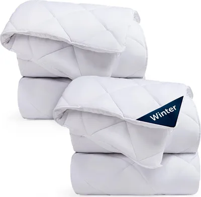 Two stacked white comforters, one with a dark blue tag that says "Winter".