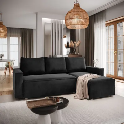 A modern living room with a black sectional sofa, coffee table, and decorative elements.