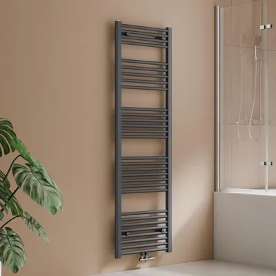 A dark grey towel radiator is mounted on a light brown wall next to a bathtub with a glass shower screen.