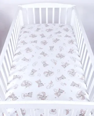 A white crib with a fitted sheet featuring a pattern of beige teddy bears and clouds.