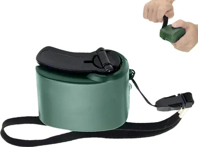 A green hand-crank USB charger with a black strap and buckle, shown in isolation with a small inset image of hands using it.
