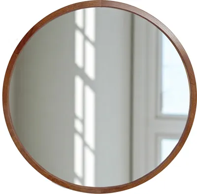 A round mirror with a wooden frame is shown against a light-colored wall with window light reflections.