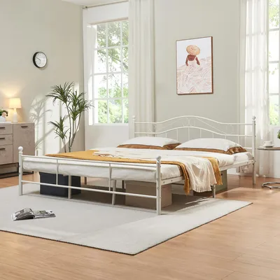 A white metal bed frame with bedding in a bedroom setting.