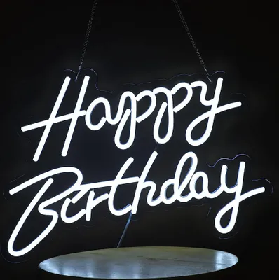 A white neon sign spelling out "Happy Birthday" hangs against a black background.