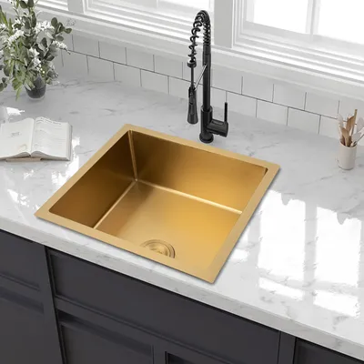 A gold kitchen sink with a black faucet is shown on a marble countertop.