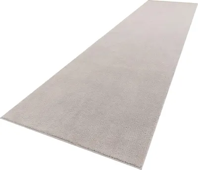 A long, narrow, light gray rug is shown from a diagonal, slightly elevated perspective against a white background.