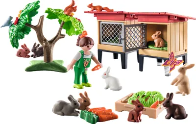 A collection of Playmobil figures and accessories, including a girl, rabbits, a rabbit hutch, a tree with squirrels and a bird, and carrots.
