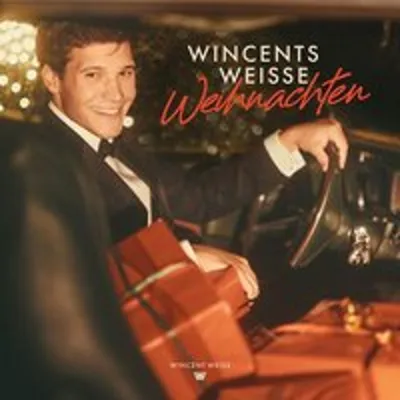 A man in a tuxedo driving a vintage car with Christmas presents.