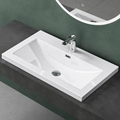 A white rectangular sink with a chrome faucet is installed on a dark gray countertop against a dark green wall.