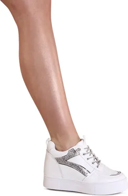 A person's leg wearing a white sneaker with silver glitter accents.