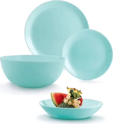 A set of turquoise dishes and bowls, with a small bowl of fruit in the foreground.