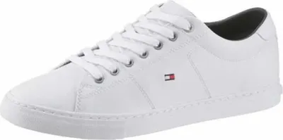 A white Tommy Hilfiger sneaker is shown from a side angle against a white background.