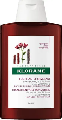 A bottle of Klorane shampoo with a label showing botanical illustrations and product information.