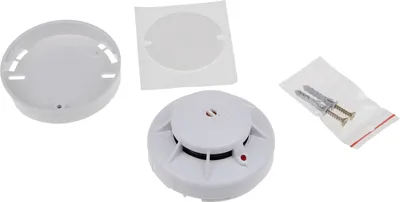 A white smoke detector and its accessories are laid out on a white background.