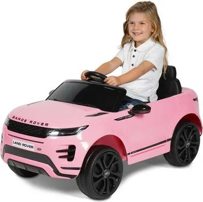 A young girl is sitting in a pink toy Range Rover.