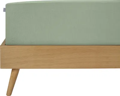A close-up view of a bed frame with a light green fitted sheet.