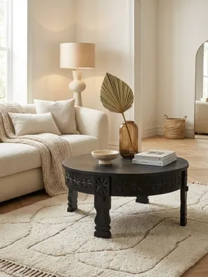Eleganter runder Couchtisch aus schwarzem Massivholz im orientalischen Stil, stilvoll in einem hellen Wohnzimmer mit einem cremefarbenen Teppich und einem gemütlichen Sofa arrangiert._#sku_SAFWL6.350#