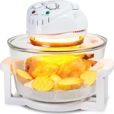 A halogen oven with a chicken and potatoes inside, on a white background.
